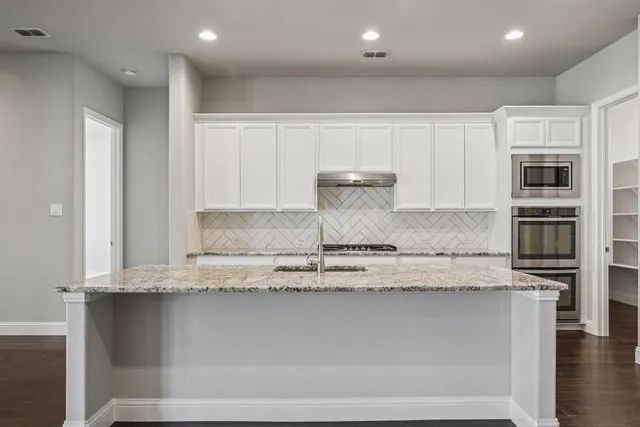 a kitchen with granite countertop a sink and cabinets