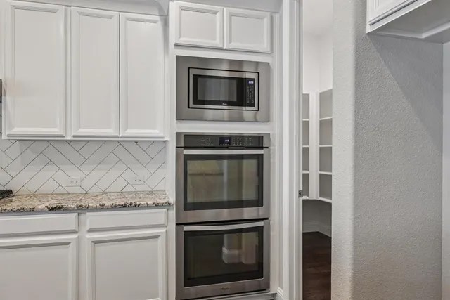 a kitchen with granite countertop white cabinets stainless steel appliances and a sink