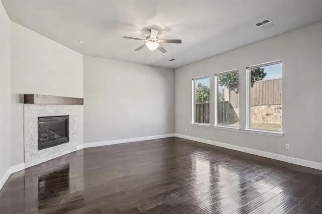 a view of an empty room with wooden floor fireplace and a window