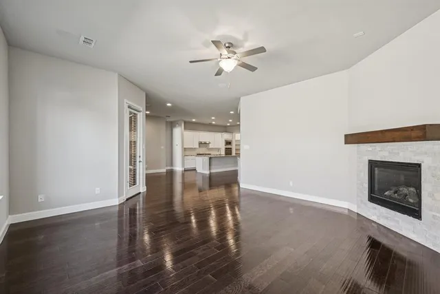 a view of a livingroom with a fireplace wooden floor and a kitchen