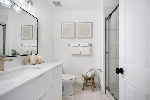 a bathroom with a granite countertop toilet sink and mirror