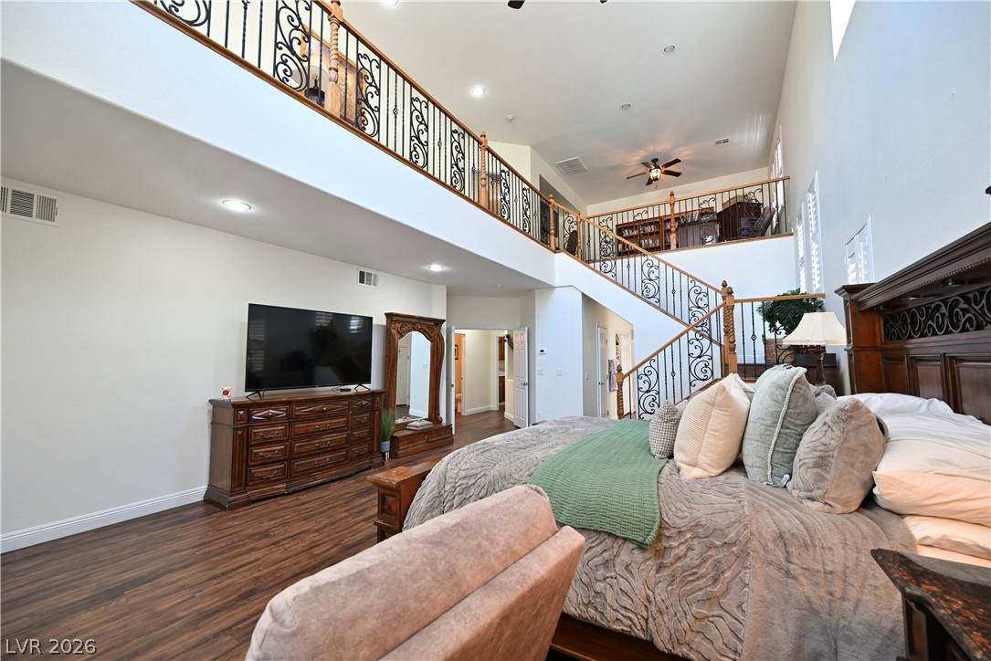 2729 Kildrummie Street Henderson, NV 89044 - Photo 7 of 42 A spacious primary bedroom features soaring ceilings and elegant wood flooring, creating an open and refined ambiance.