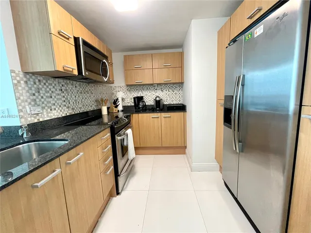 a kitchen with stainless steel appliances granite countertop a refrigerator a stove a sink and a microwave