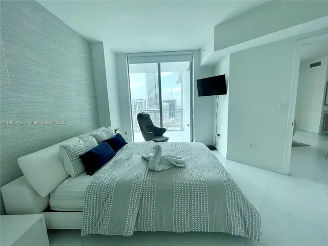 a bedroom with a bed and large windows