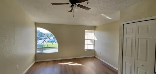 an empty room with windows and fan