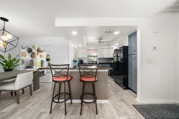 a kitchen with stainless steel appliances kitchen island granite countertop a refrigerator a stove a microwave oven with white cabinets and wooden floor