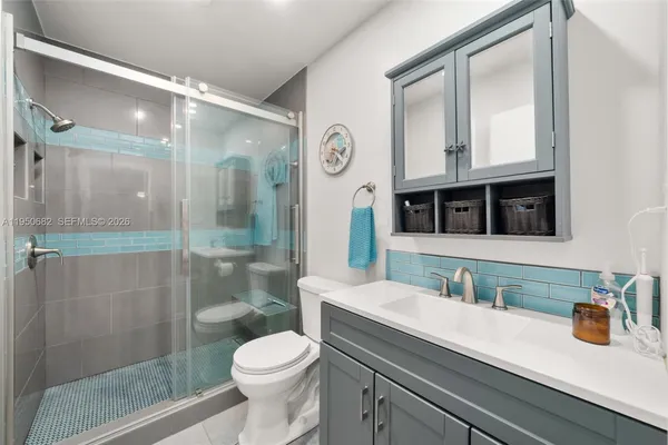 a bathroom with a sink a toilet a shower and a mirror