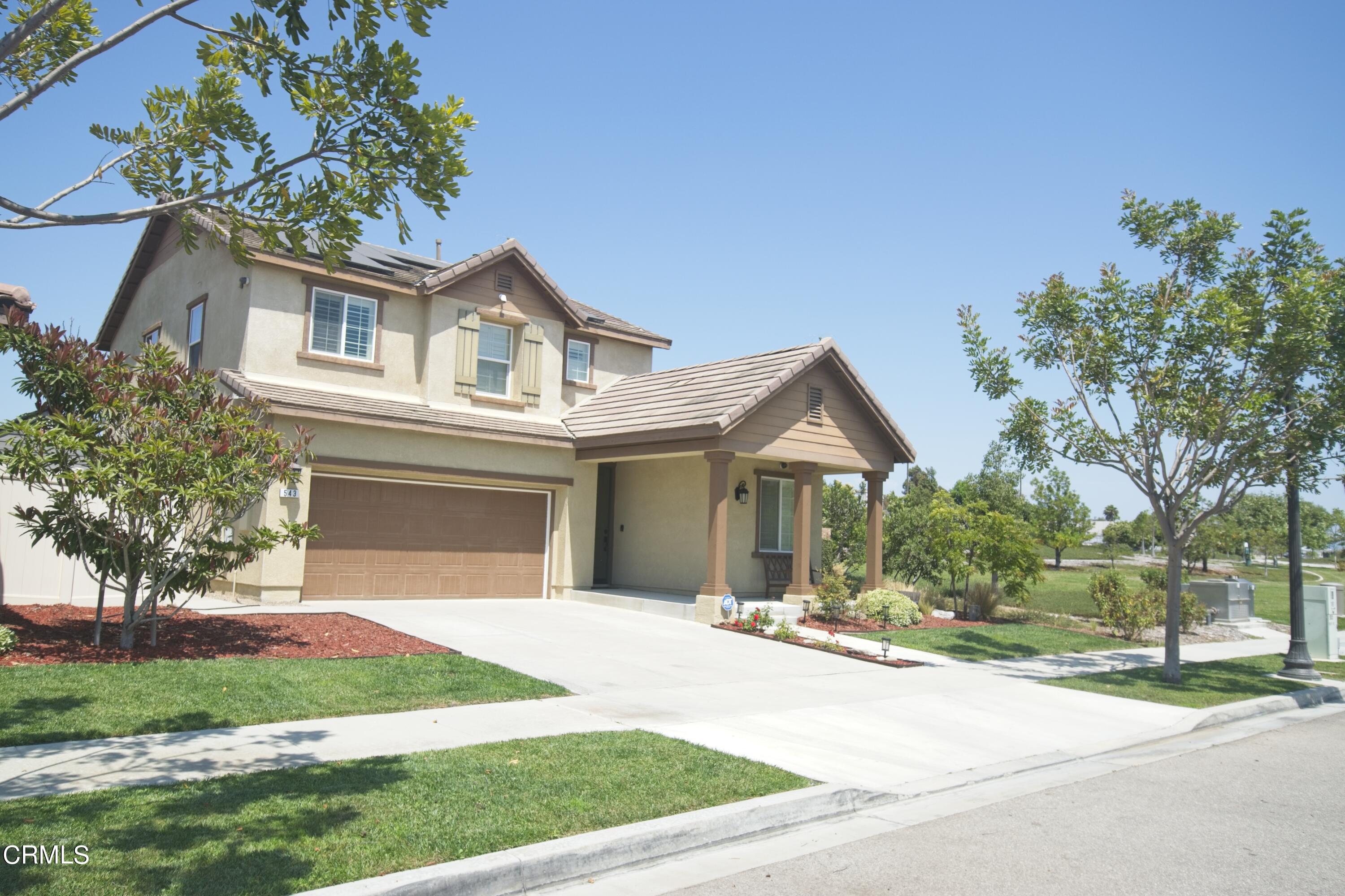 a front view of a house with a garden and trees