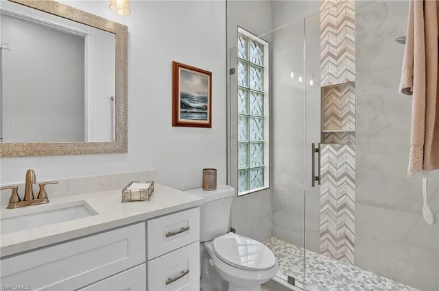 a bathroom with a granite countertop sink a toilet a shower and a mirror