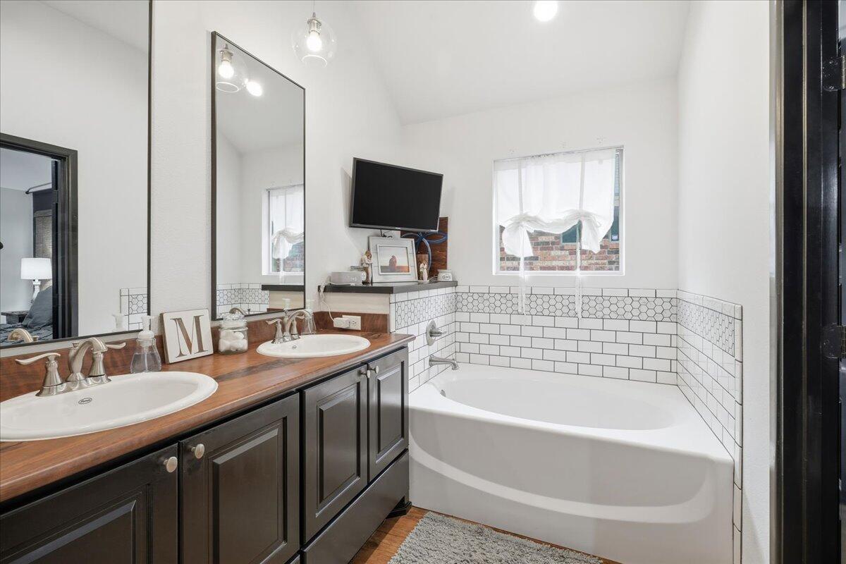 3013 111th Street Lubbock, TX 79423 - Photo 21 of 37 a bathroom with a tub double sink window and mirror