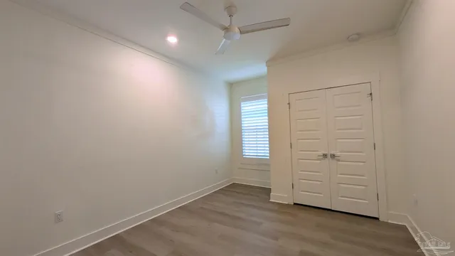 an empty room with wooden floor closet and windows