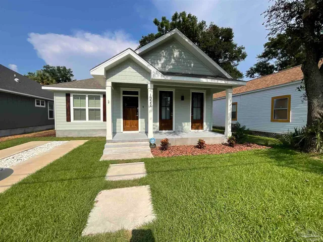 a front view of a house with a yard and potted plants