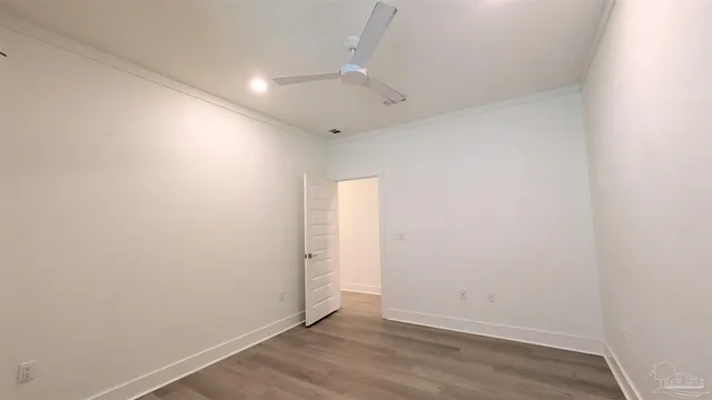 an empty room with wooden floor and fan