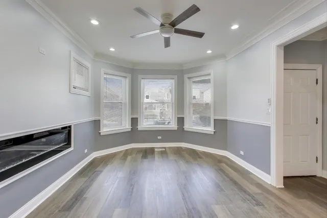 a view of a room with wooden floor a ceiling fan and windows