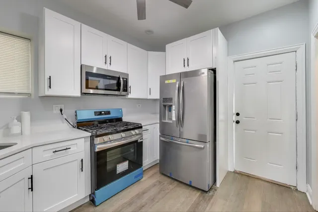a kitchen with cabinets stainless steel appliances a sink and wooden floor