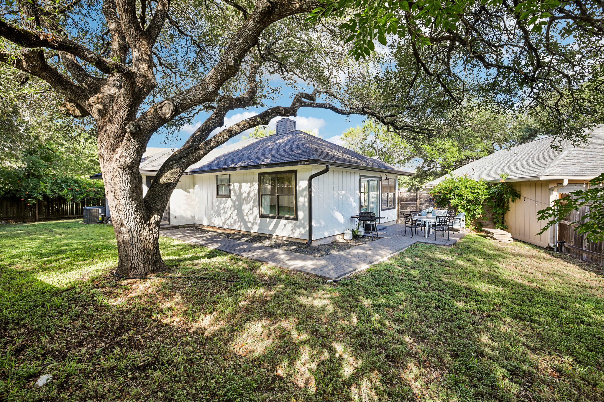 16725 Whitebrush Loop Austin, TX 78717 - Photo 25 of 32 Mature shade trees canopy a paved patio overlooking the grassy backyard lawn.