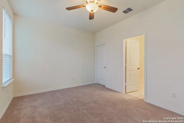 an empty room with chandelier fan and windows