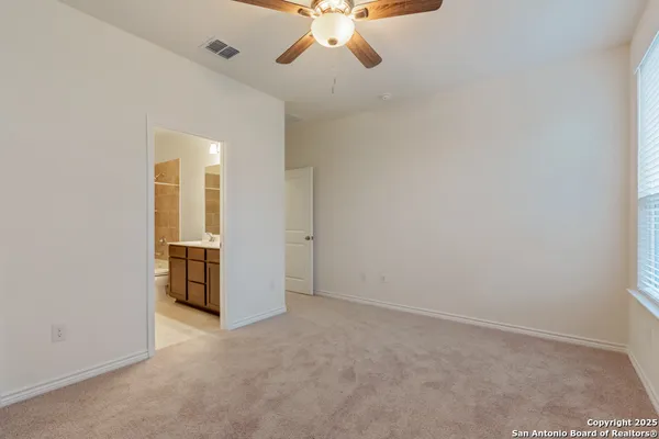 an empty room with chandelier fan and windows