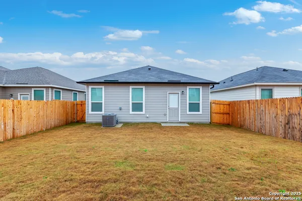 a view of a house with backyard and wooden fence