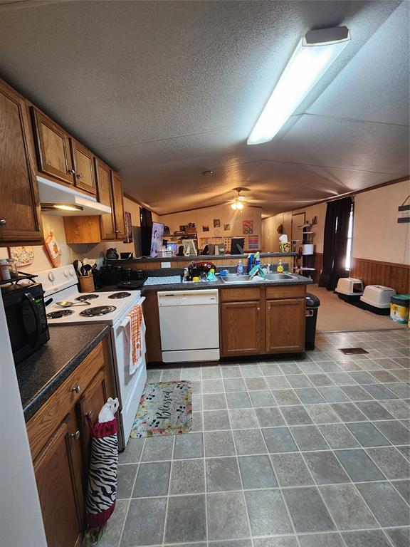 7120 Golden Meadows Road Greenwood, LA 71033 - Photo 4 of 14 Kitchen with brown cabinets, dark countertops, range, dishwashing machine, and a wainscoted wall
