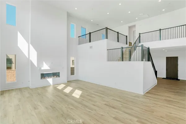 a view of a big room with wooden floor and a kitchen