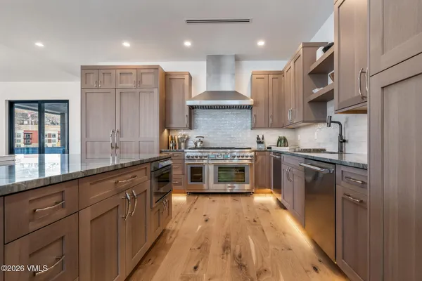 a kitchen with stainless steel appliances granite countertop a stove a sink and a refrigerator