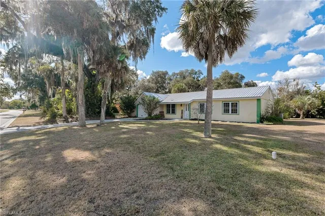 a front view of a house with a garden and trees