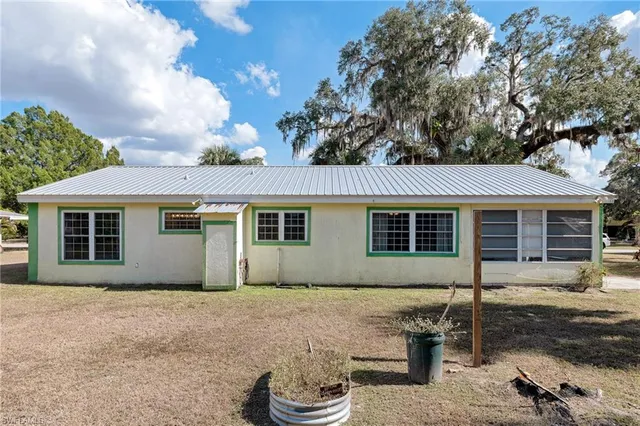 a front view of house with yard and trees in the background