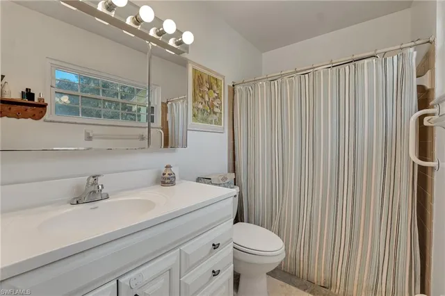 a bathroom with a sink a toilet a mirror and shower curtain