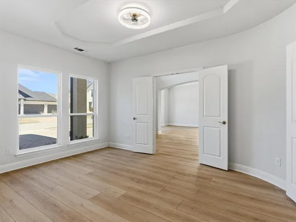 an empty room with wooden floor and windows