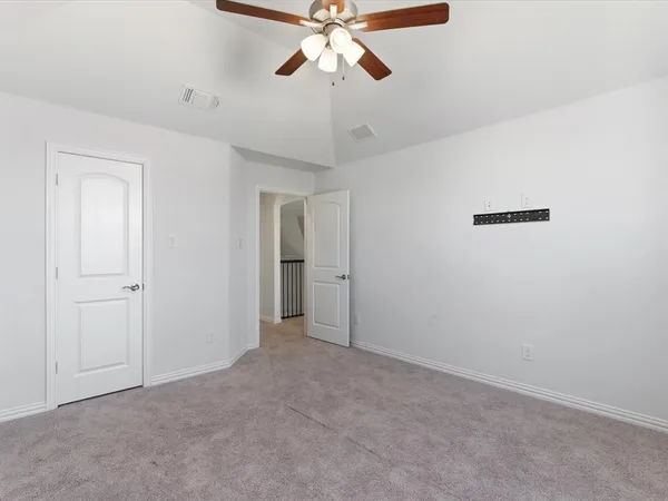 a view of an empty room and chandelier fan