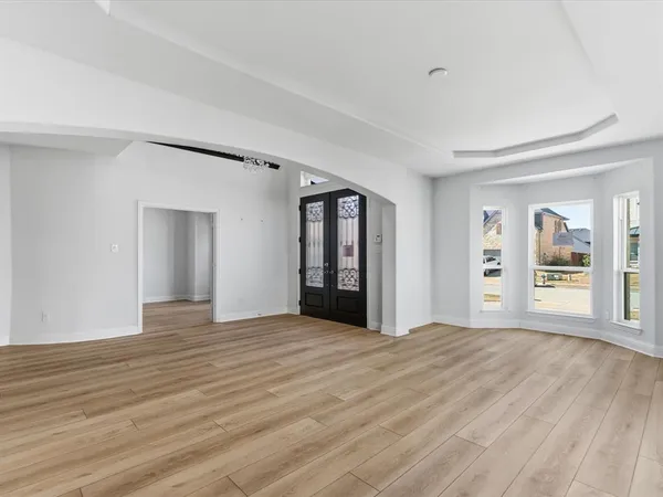 a view of an empty room with window and wooden floor