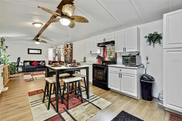 a kitchen with stainless steel appliances kitchen island granite countertop a stove refrigerator a sink dishwasher a dining table and chairs with wooden floor