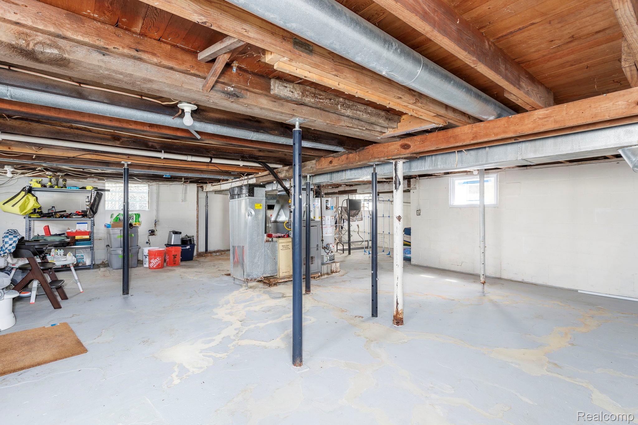 401 Pointe Tremble Road Algonac, MI 48001 - Photo 39 of 40 Unfinished basement featuring exposed wood ceiling joists and support beams, white painted concrete walls, and a concrete floor