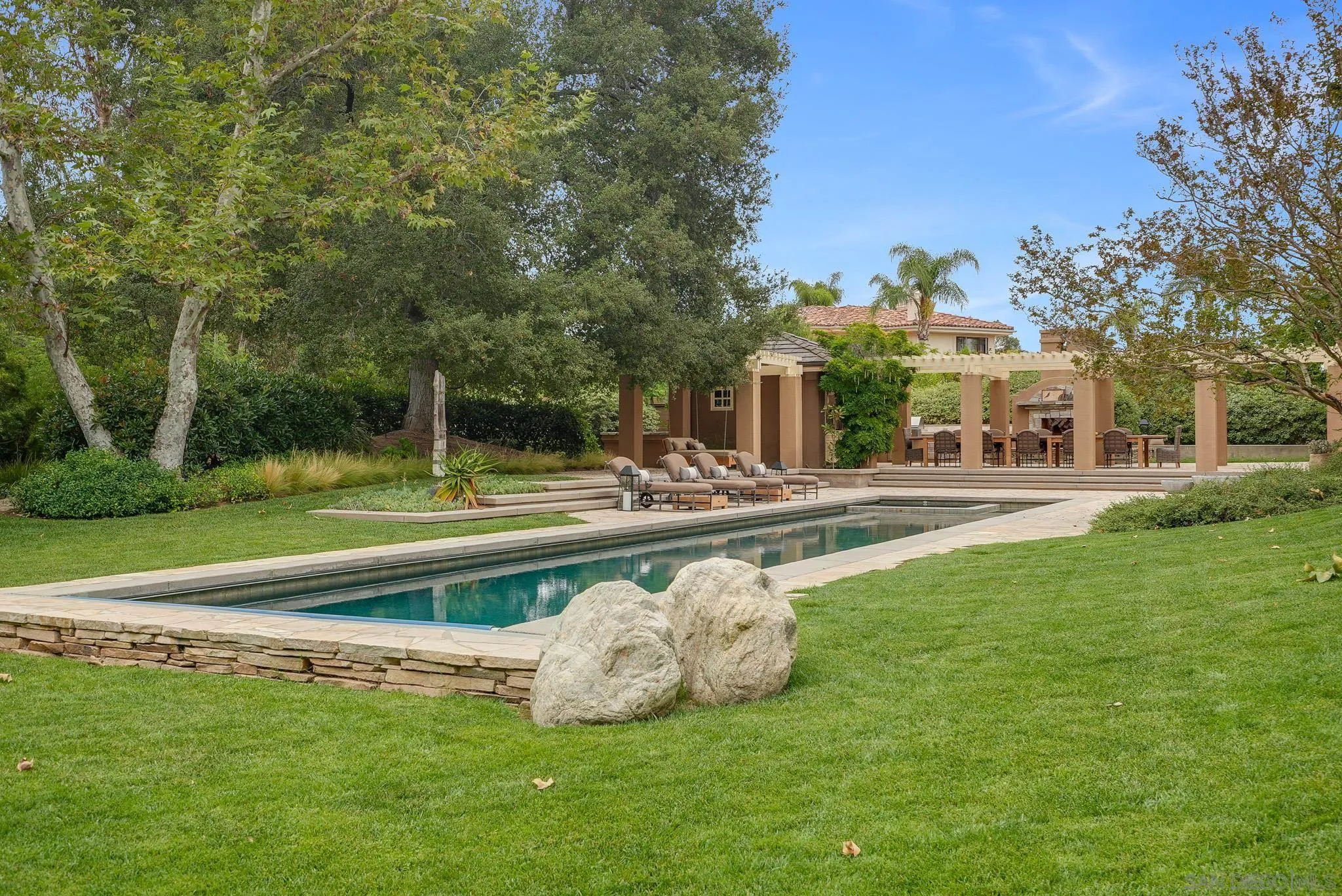 7891 Muirfield Way Rancho Santa Fe, CA 92067 - Photo 3 of 47 a front view of a building with a garden and trees