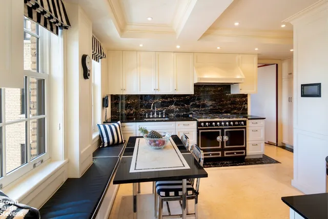 a kitchen with stainless steel appliances kitchen island granite countertop a stove a refrigerator a sink a dining table and chairs with wooden floor