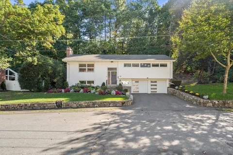 a view of a house with a yard and large trees
