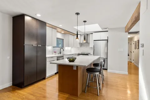 a kitchen with stainless steel appliances a dining table chairs refrigerator and cabinets