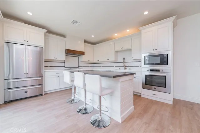 a kitchen with stainless steel appliances granite countertop a stove a sink dishwasher and a refrigerator with wooden floor