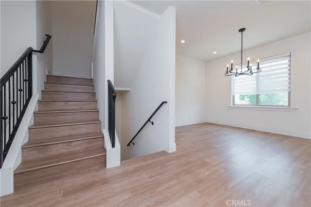 an empty room with wooden floor chandelier and windows