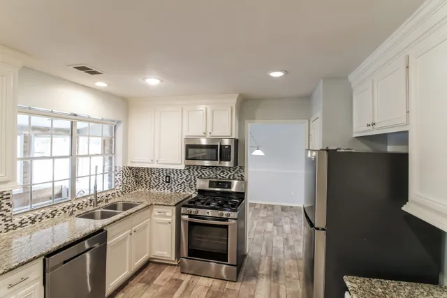 a kitchen with stainless steel appliances granite countertop a stove a refrigerator and a sink