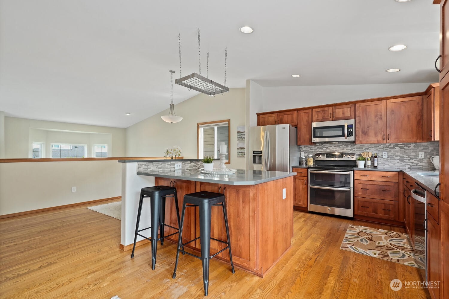 1326 238th Place Southwest Bothell, WA 98021 - Photo 10 of 34 a kitchen with stainless steel appliances granite countertop a kitchen island hardwood floor sink stove dining table and chairs