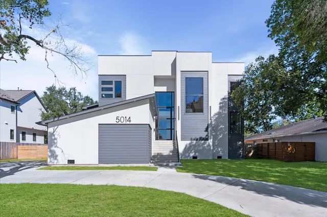 a view of a house with a yard and a large tree