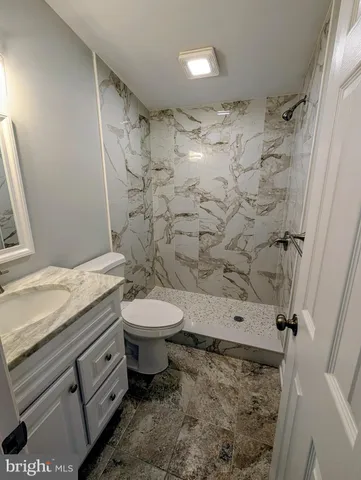 a bathroom with a granite countertop toilet a sink and a shower