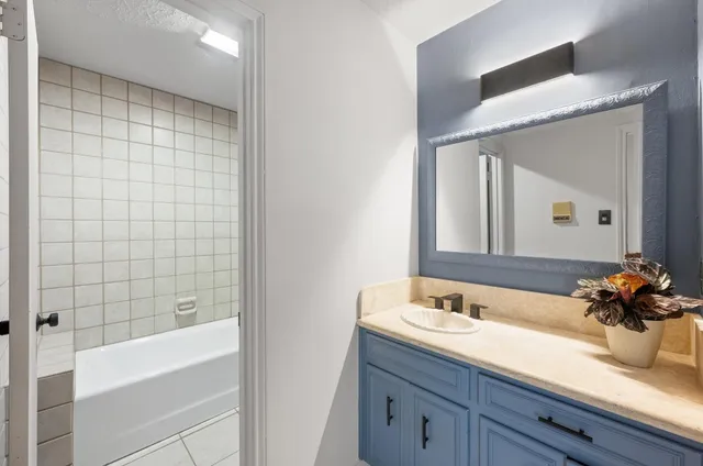 a bathroom with a granite countertop sink a toilet a mirror and bathtub