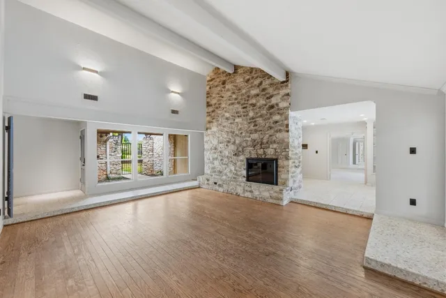 an empty room with windows and fireplace