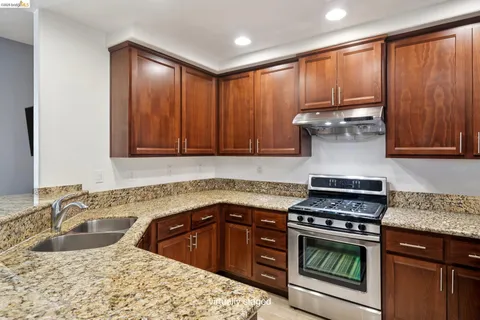 a kitchen with granite countertop a sink stove and cabinets