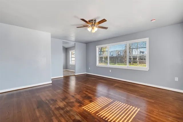 a view of an empty room with wooden floor and a window