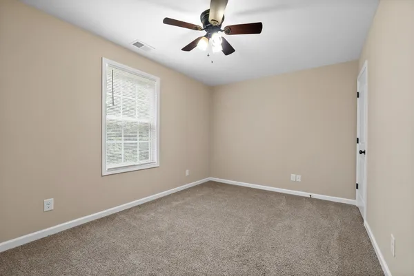 an empty room with windows and fan