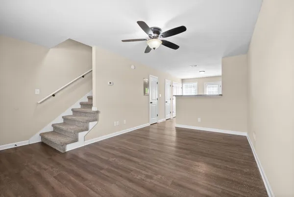 a view of an empty room with wooden floor and a ceiling fan